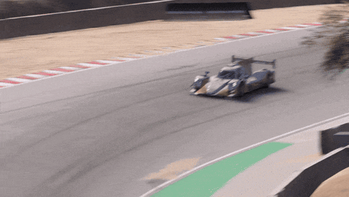 a race car is going around a curve on a track with a green curb