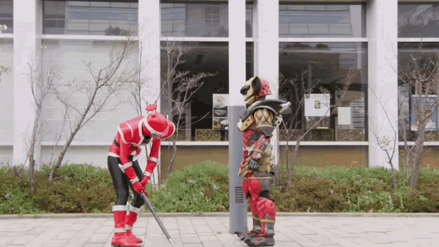 a man in a red superhero costume is standing next to another man in a gold costume