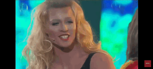 a blonde woman with a microphone in her mouth is smiling