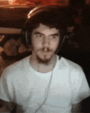 a man wearing headphones and a white t-shirt looks at the camera
