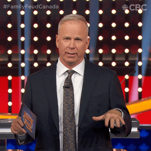 a man in a suit and tie is standing in front of a screen that says family feud canada on it