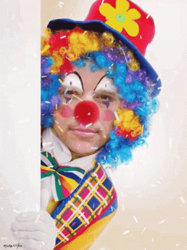 a man dressed as a clown is holding a white board