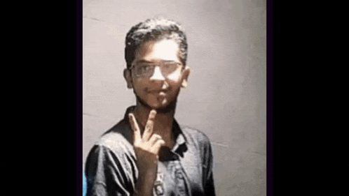a young man wearing glasses is making a peace sign with his hand .