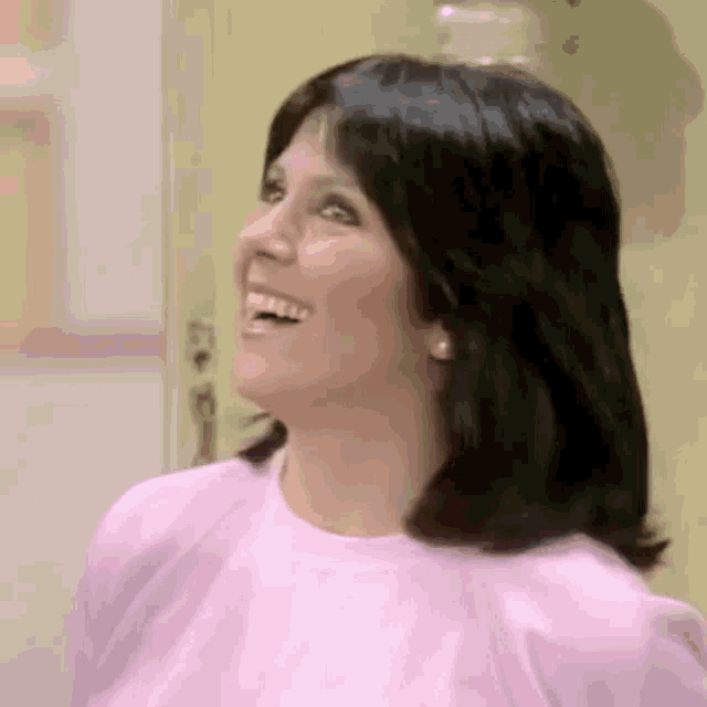 the woman is wearing a pink shirt and smiling .