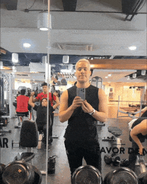 a man taking a picture of himself in a gym with the word favor on the bottom right corner