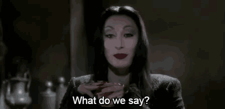 a woman in a black dress is holding a cup and asking what do we say .