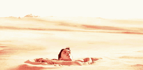 a shirtless man is sitting in the sand in the desert .