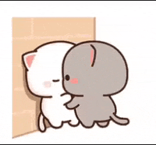 a white cat and a gray cat are hugging each other in a corner .
