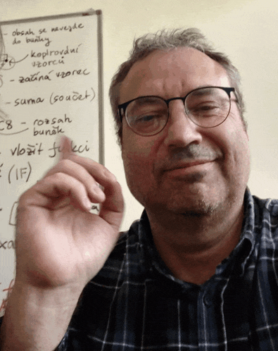 a man wearing glasses is smiling in front of a whiteboard that says obsah se navejde