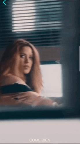 a woman is standing in front of a window with the words come bien on the bottom right