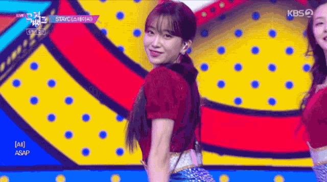 a woman in a red shirt is dancing on a colorful stage