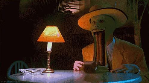 a man with a green mask is sitting at a table with a lamp