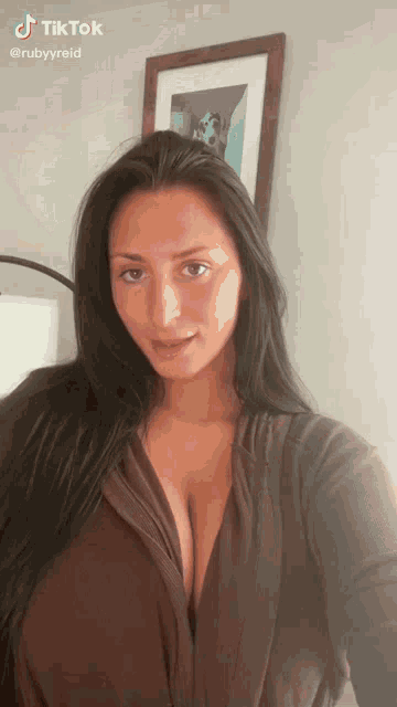 a woman with long black hair is taking a selfie in front of a picture .