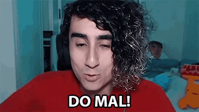 a man with curly hair is wearing headphones and making a funny face and saying `` do mal '' .