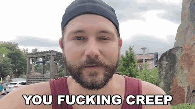 a man with a beard says " you fucking creep " while wearing a hat