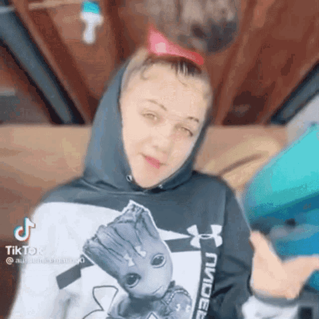 a girl wearing a hoodie with a groot on it is holding a gun .