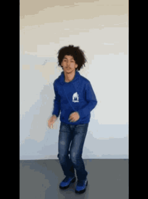a young man wearing a blue hoodie is dancing