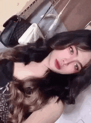 a woman with long hair is laying on a bed with a purse .