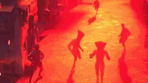 a group of people are walking down a street in a dark room with red lights .
