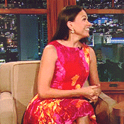 a woman in a floral dress is sitting in a chair