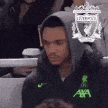 a man wearing a liverpool hoodie is sitting in the stands