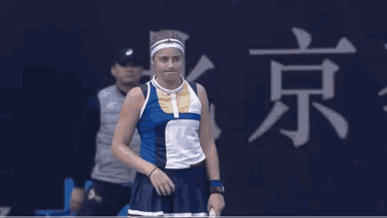 a woman holding a tennis racquet in front of a wall with chinese characters
