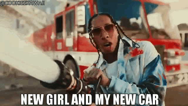 a man in sunglasses is holding a fire extinguisher in front of a fire truck .