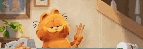garfield the cat is giving a peace sign while sitting at a desk