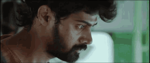 a close up of a man 's face with a beard looking at something .