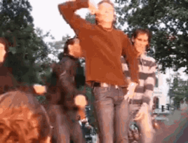 a man in a brown sweater is dancing in a crowd of people .