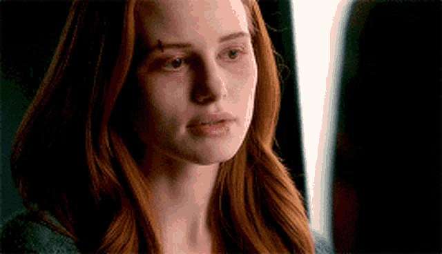 a close up of a woman 's face with red hair looking at the camera .