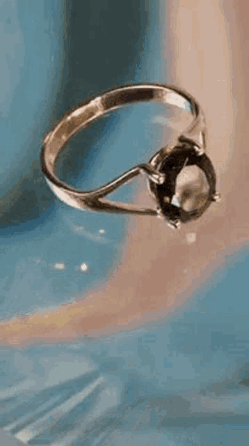 a close up of a ring with a green stone on a blue surface .