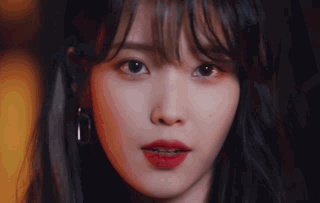 a close up of a woman 's face with red lipstick and earrings