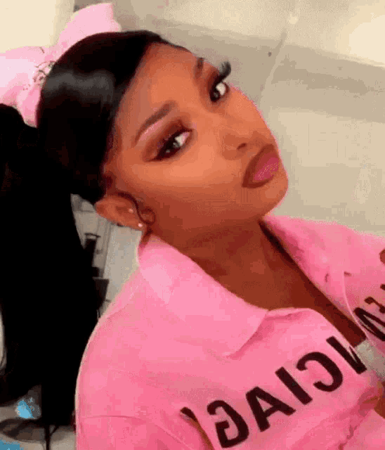 a close up of a woman wearing a pink shirt and a pink bow on her head .