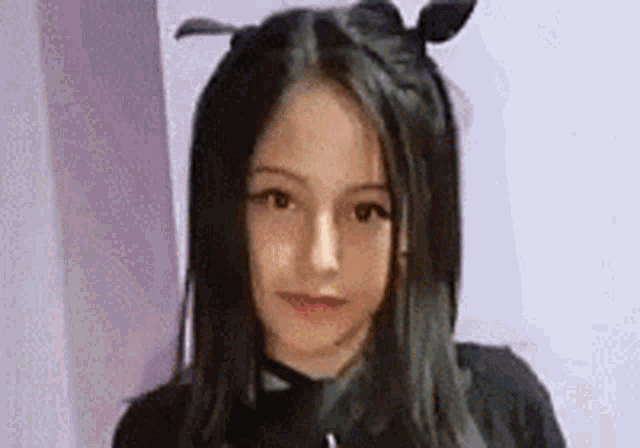 a young girl with long black hair and bunny ears is wearing a black shirt .