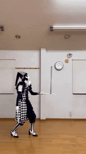 a man in a harlequin costume is holding a stick in a room