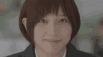 a close up of a woman 's face with short hair and a smile .
