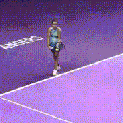 a woman walking on a purple tennis court with the word angels written on the floor