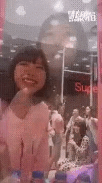 a woman is smiling in front of a mirror with a sign that says supreme in the background .