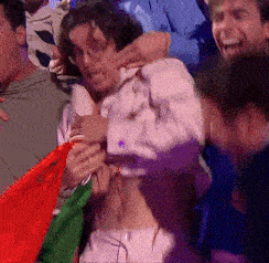 a man in a white shirt is being held by a crowd