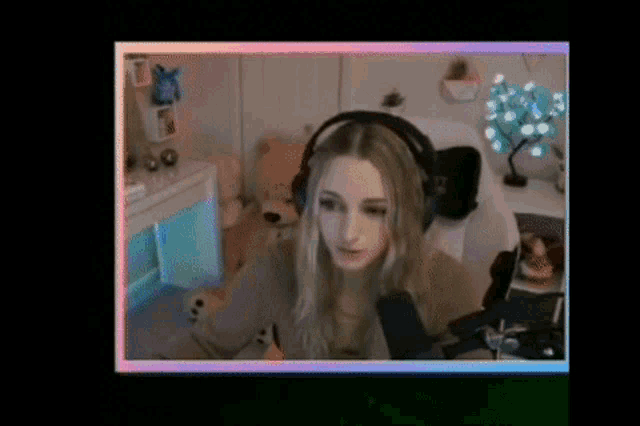 a woman wearing headphones is sitting in front of a microphone on a computer screen .