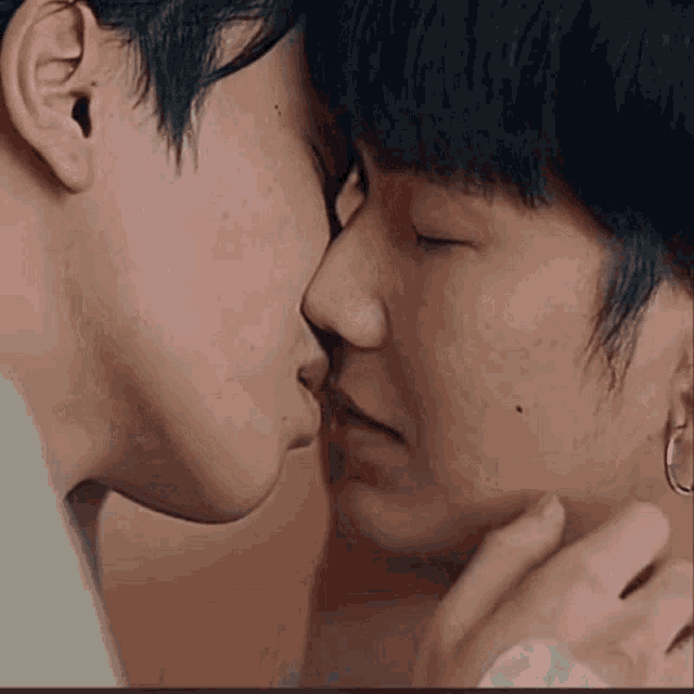 a couple of men are kissing each other in a close up of their faces .