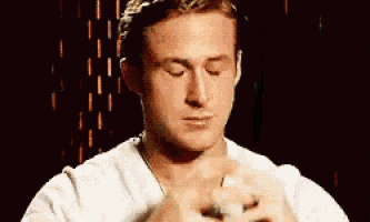 a close up of a man 's face with his eyes closed and his hands folded in prayer .