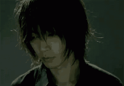 a close up of a man 's face with long hair and a black shirt .