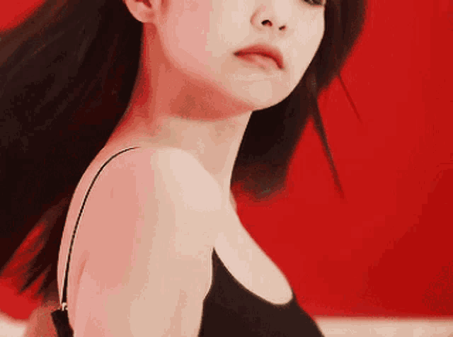 a woman in a black tank top looks at the camera with her hair blowing in the wind