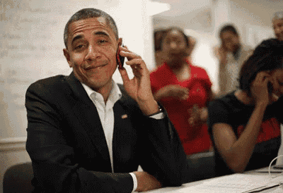 barack obama is smiling while talking on his cell phone