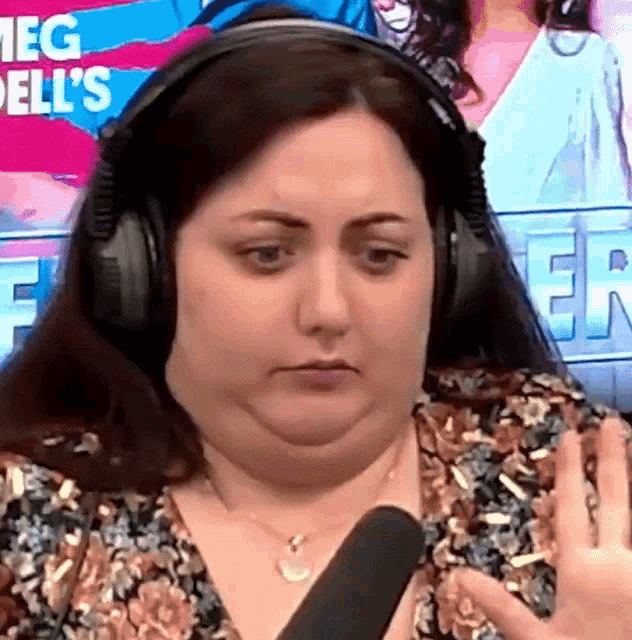 a woman wearing headphones talks into a microphone in front of a screen that says meg dell 's