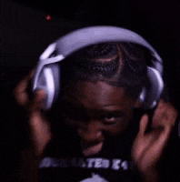 a man wearing headphones is smiling and wearing a black shirt with the word x4 on it .