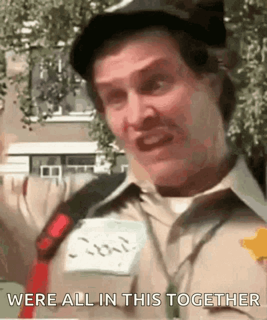 a man wearing a hat and a name tag with the words were all in this together written on it
