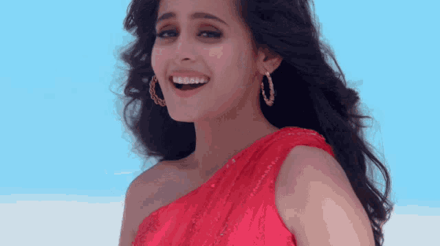 a woman in a red one shoulder dress is smiling